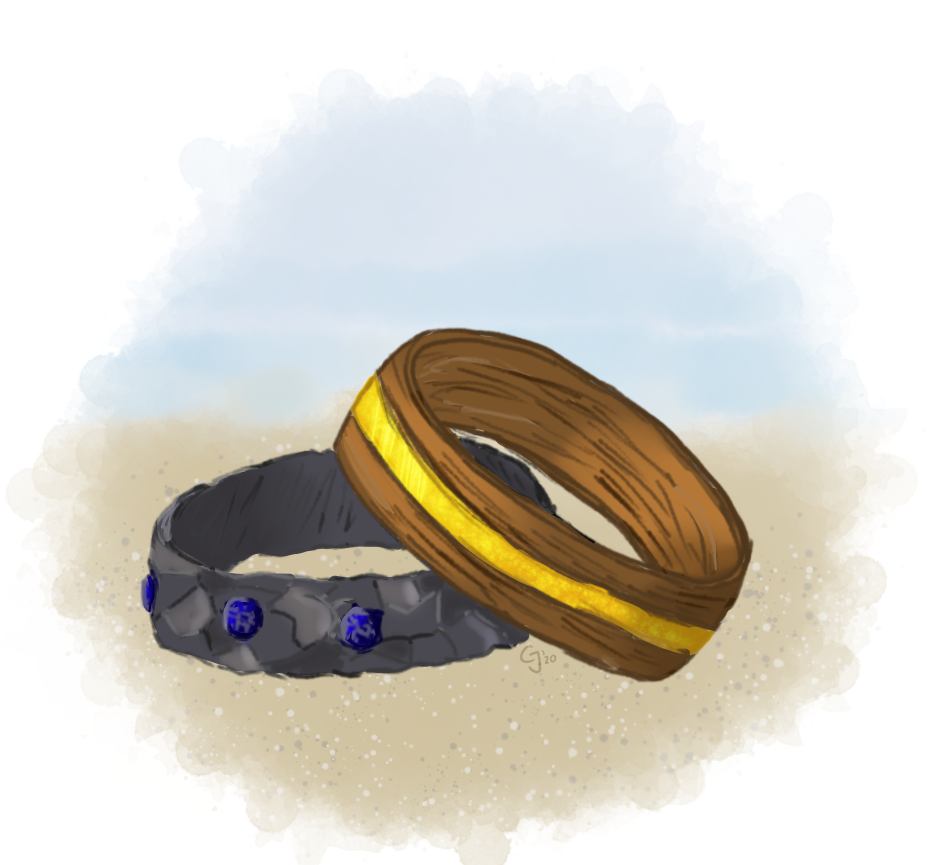 Two rings in the sand. One is dark metal and blue stones, the other is wood with an inlayed amber stripe.